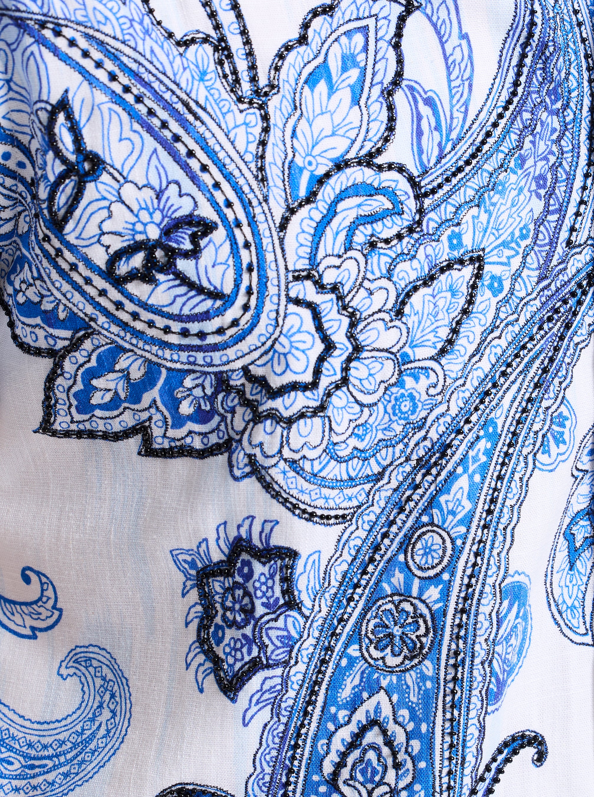 Close-up of a blue and black beaded paisley pattern on a white background