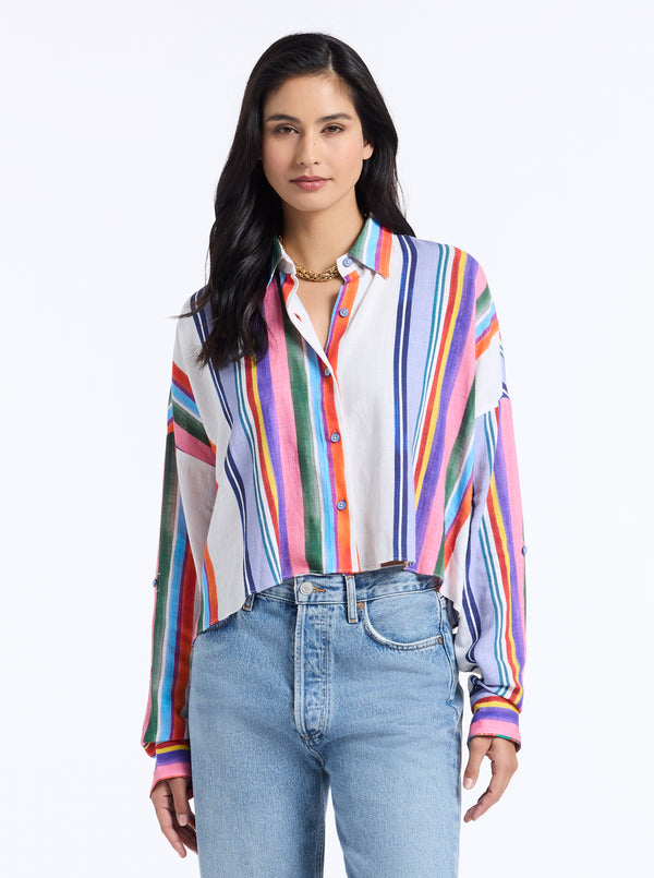 Woman wearing a colorful striped shirt and blue jeans on a white background