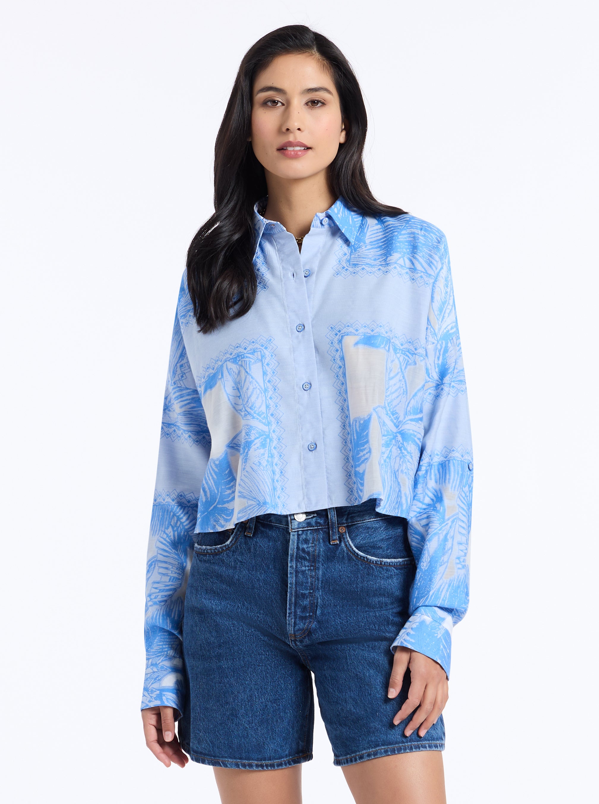 Woman wearing a blue shirt and denim shorts on a white background